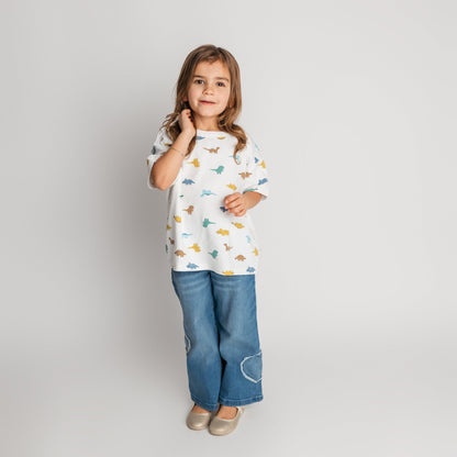 Child modeling white soft cotton t-shirt in cool dino print with an oversized style